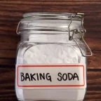 Буркан с надпис „Baking Soda“, пълен със сода бикарбонат, поставен върху дървена маса