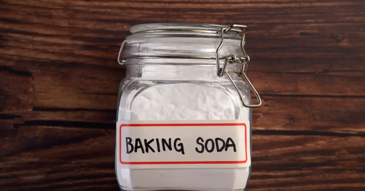 Буркан с надпис „Baking Soda“, пълен със сода бикарбонат, поставен върху дървена маса